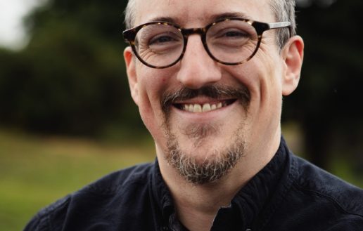a headshot of paddy wearing a black shirt